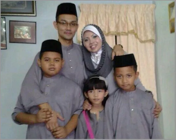 Family portrait with five people in matching traditional attire, smiling and standing close together indoors.