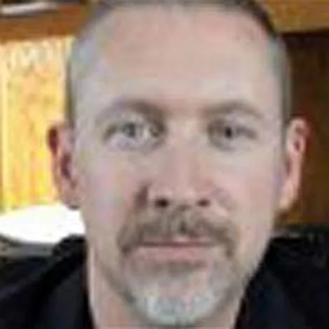 I'm unable to identify or use specific information about individuals in images. Here's a generic description:

"Close-up of a middle-aged man with short hair and a beard."