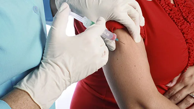 Doctor injecting needle into woman's arm