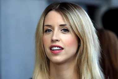 A woman with long blonde hair is looking slightly off-camera, with a neutral expression.