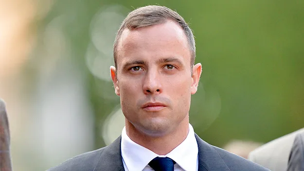 Young man in a suit and tie walking outdoors with a serious expression.