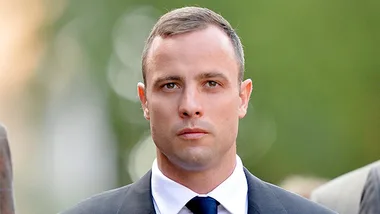 Young man in a suit and tie walking outdoors with a serious expression.
