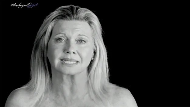 A woman in a black-and-white image, delivering a message for a breast cancer awareness campaign.