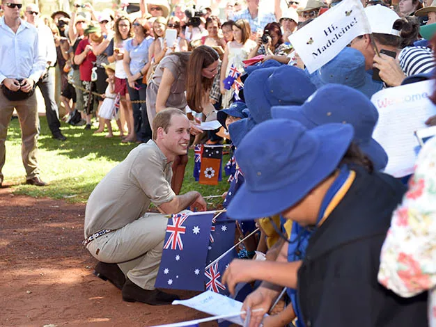 Prince interacts with children holding Australian flags at a public event.