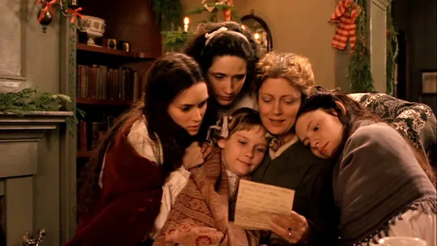 A family gathers closely around a letter, dressed in 19th-century attire in a cozy, holiday-decorated room.