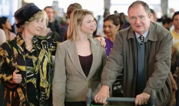 Bridget Jones arriving at the airport with her parents, surrounded by a busy crowd.