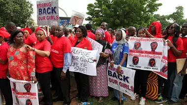 People in red shirts holding signs for the #BringBackOurGirls campaign, advocating for kidnapped Nigerian girls' return.