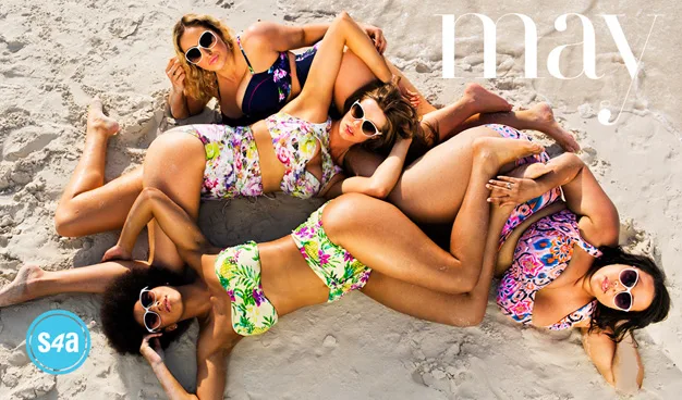 Four women in colorful swimsuits and sunglasses lying on sand, forming a circle. The word "May" is in the top corner.