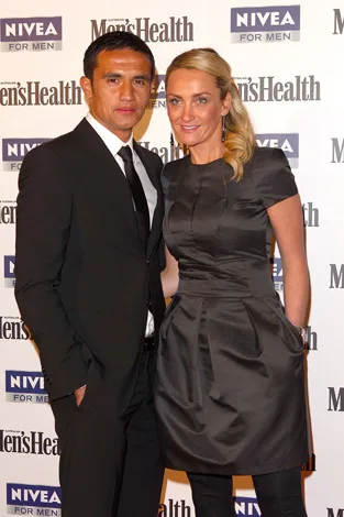 A man in a suit and a woman in a black dress pose together at a Men's Health and Nivea event.