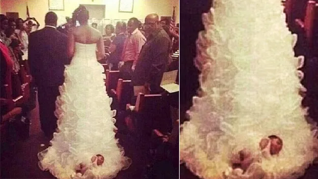 Bride walking down aisle with baby attached to wedding dress train.