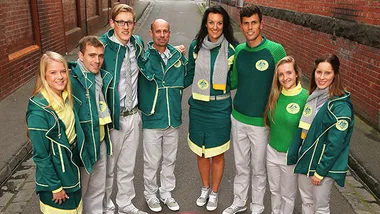 Australian athletes wearing green and yellow Commonwealth Games uniforms with jackets, sweaters, and scarves, standing in a row.
