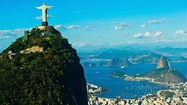Christ the Redeemer statue overlooking Rio de Janeiro with Sugarloaf Mountain in the background.