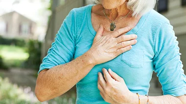 elderly woman holding chest, stock image 