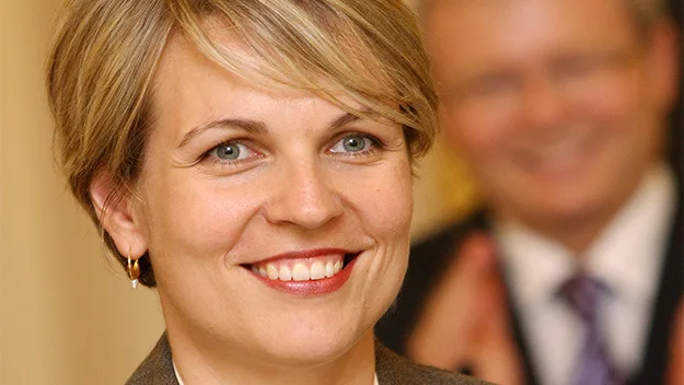 Tanya Plibersek smiling, with a blurred person clapping in the background.