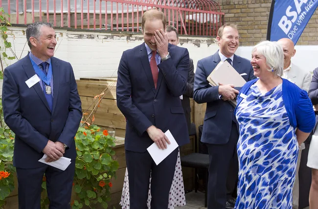 Group of people in business attire laughing outdoors at an event.