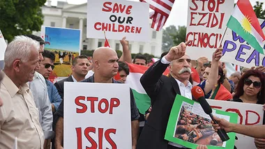 Protesters hold signs against ISIS, advocating peace and justice, during a demonstration outside a government building.