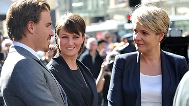 Three people conversing outdoors in a busy urban setting.
