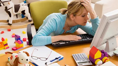 stock image, women stressed out at home on computer with toys in background