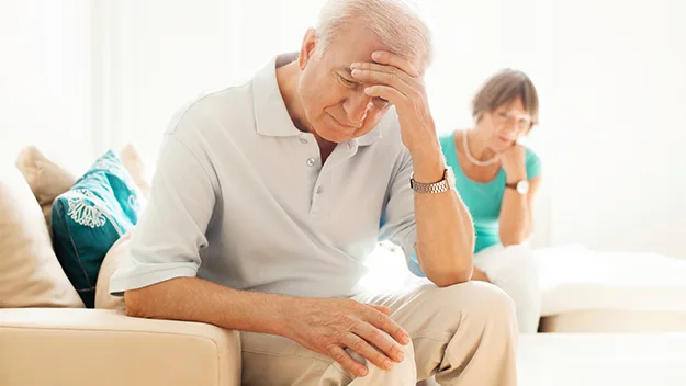 old man with head in his hands, woman in background, stock image