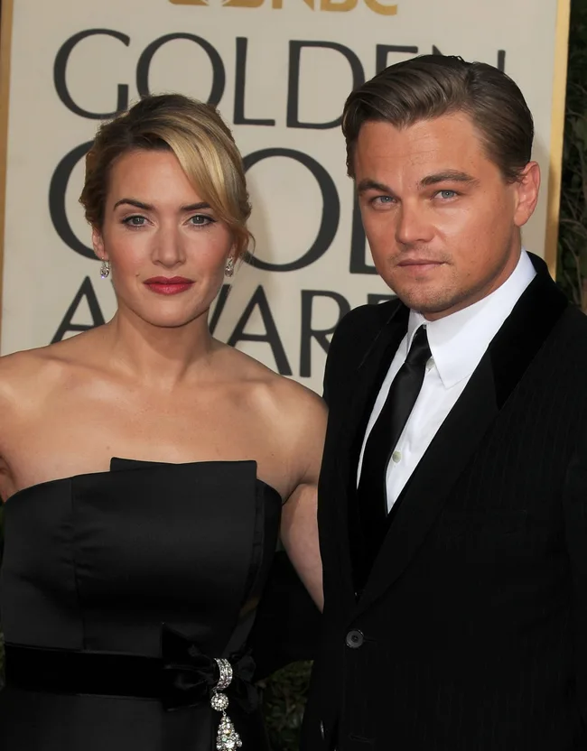 A man and woman dressed formally, posing together at an event with a "Golden Globe Awards" backdrop.