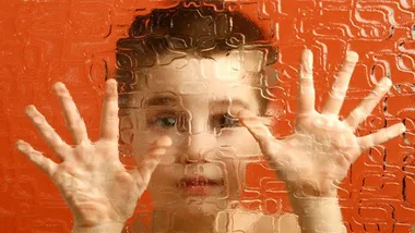 Little boy with hands up against the window 