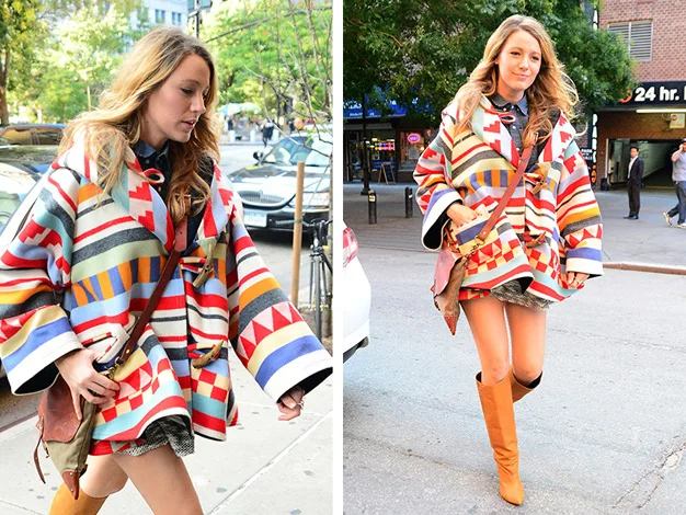 A woman in a colorful geometric coat walks down a city street, paired with tan boots and a brown crossbody bag.