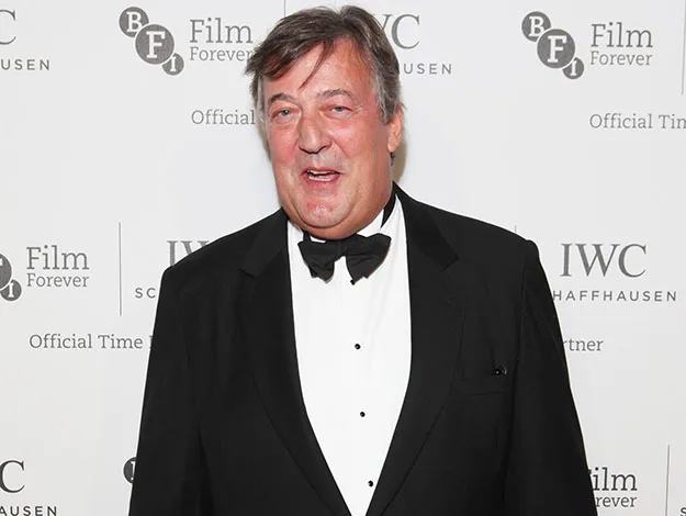 Man in a tuxedo at a BFI Film Forever event, smiling against a branded background.