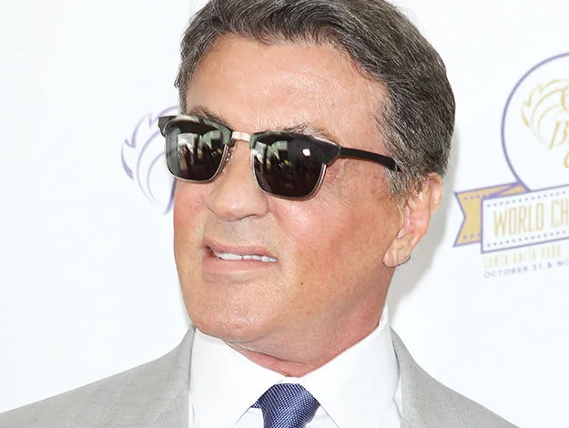 Man in sunglasses and a suit at an event, looking to the side.