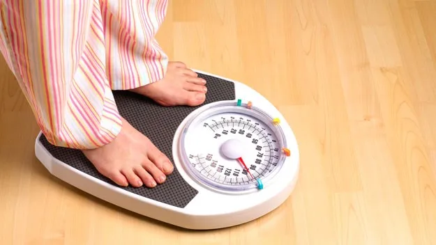 women standing on weight scale