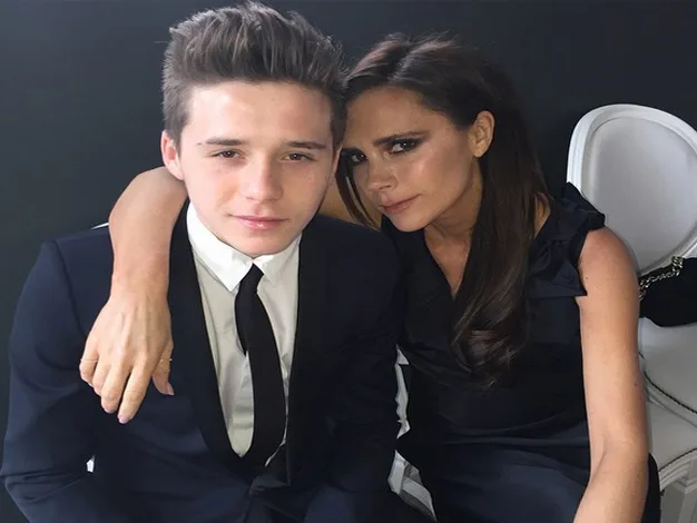 Two people dressed formally, sitting together. One has their arm around the other.