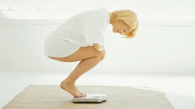 woman standing on weight scale, getty images 