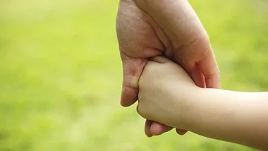 parent holding baby's hand