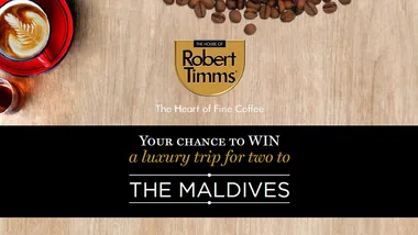 Win a luxury trip to the Maldives with Robert Timms; coffee cup and beans on a wooden surface.