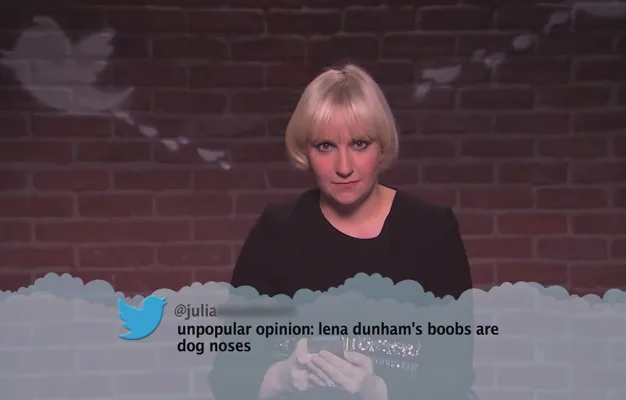 Lena Dunham reads a mean tweet about herself on a show, with a brick wall background.