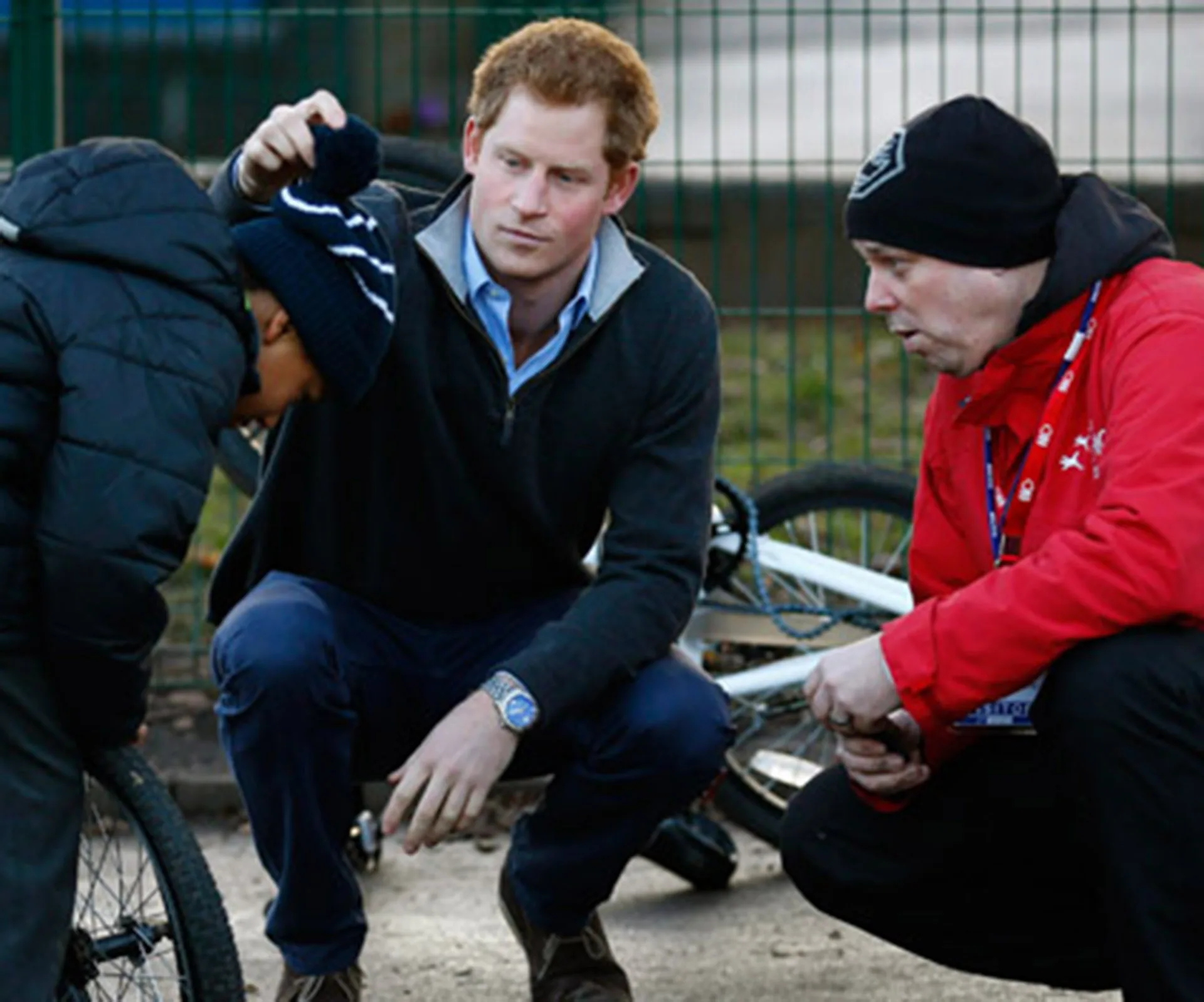 Prince Harry fixes the hat of Demani Cowin-Jenkins as EPIC worker Mick Dawber watches during a visit to the Full Effect Youth Project in Nottingham.