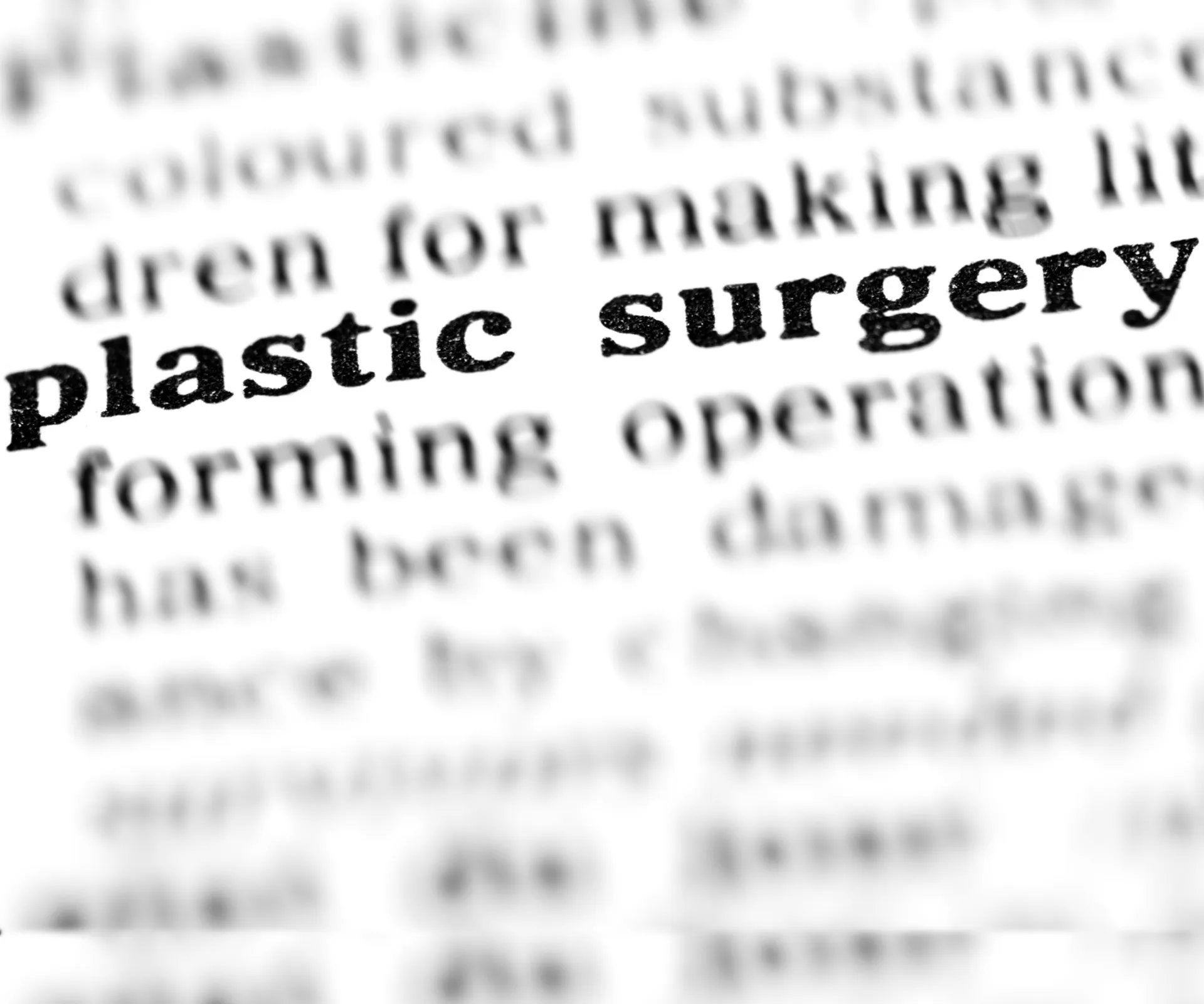 "Close-up of text in a dictionary highlighting the term 'plastic surgery' with surrounding words blurred."