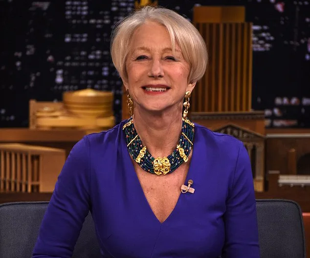 Helen Mirren on "The Tonight Show Starring Jimmy Fallon," wearing a purple dress with a colorful necklace, smiling at the camera.
