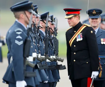 Prince in military uniform inspects soldiers in formation during a ceremonial event.