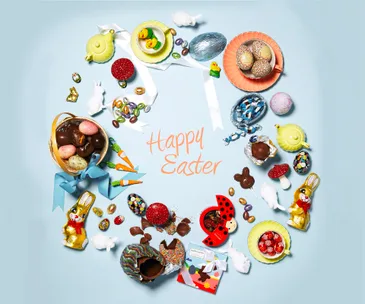Colorful Easter chocolates and candies arranged in a circle with "Happy Easter" text in the center on a light blue background.