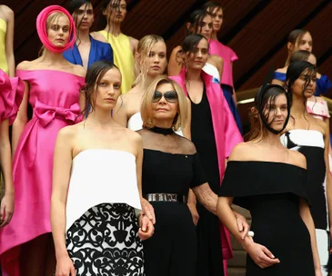 Fashion designer Carla Zampatti with models in vibrant dresses celebrating her 50th anniversary in the industry.