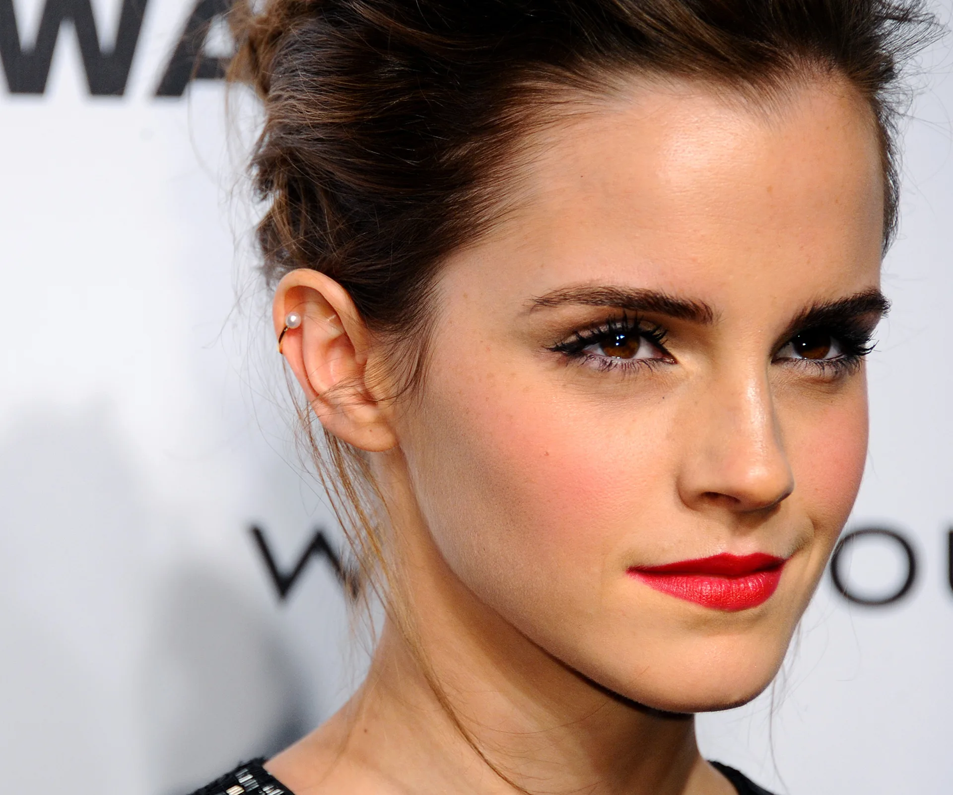 A woman with elegant makeup, red lipstick, and hair up, attending an event.