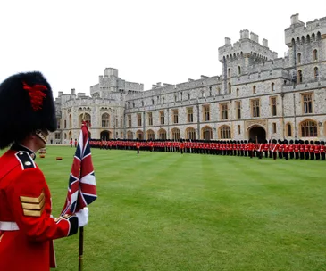 British guards in red uniforms stand ceremonially at Windsor Castle's courtyard.