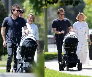 A couple smiling while walking with a stroller on a sunny day.