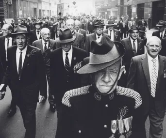 Veterans in hats march during an Anzac Day parade, with one man prominently wearing medals and a unique uniform.