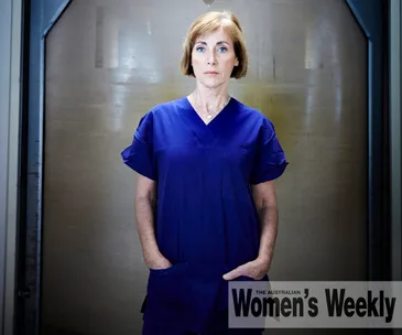 A woman in blue scrubs stands confidently with hands in pockets, against a neutral background. "Women's Weekly" logo displayed.