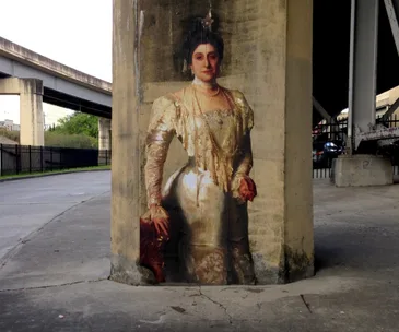 Street art depicting a woman in a classical gown on an urban concrete pillar under a highway overpass.