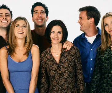 The cast of the TV show "Friends" smiling and posing together.