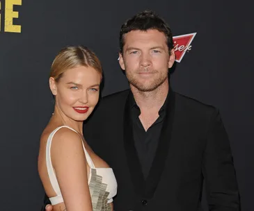 Couple posing together on the red carpet, both dressed formally, smiling at the camera.