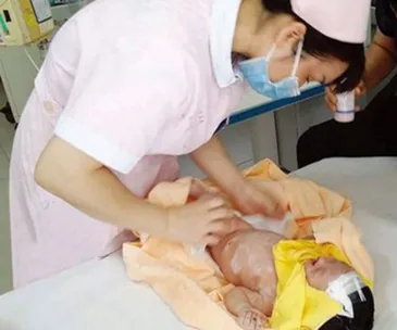 A nurse tends to a baby wrapped in a blanket on a medical table, providing care and ensuring its well-being.