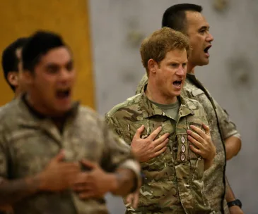 Soldiers in camouflage uniforms performing a haka, with the focus on the soldier in the middle.